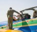 A military pilot standing by a vibrant aircraft, preparing for a mission under clear skies.
