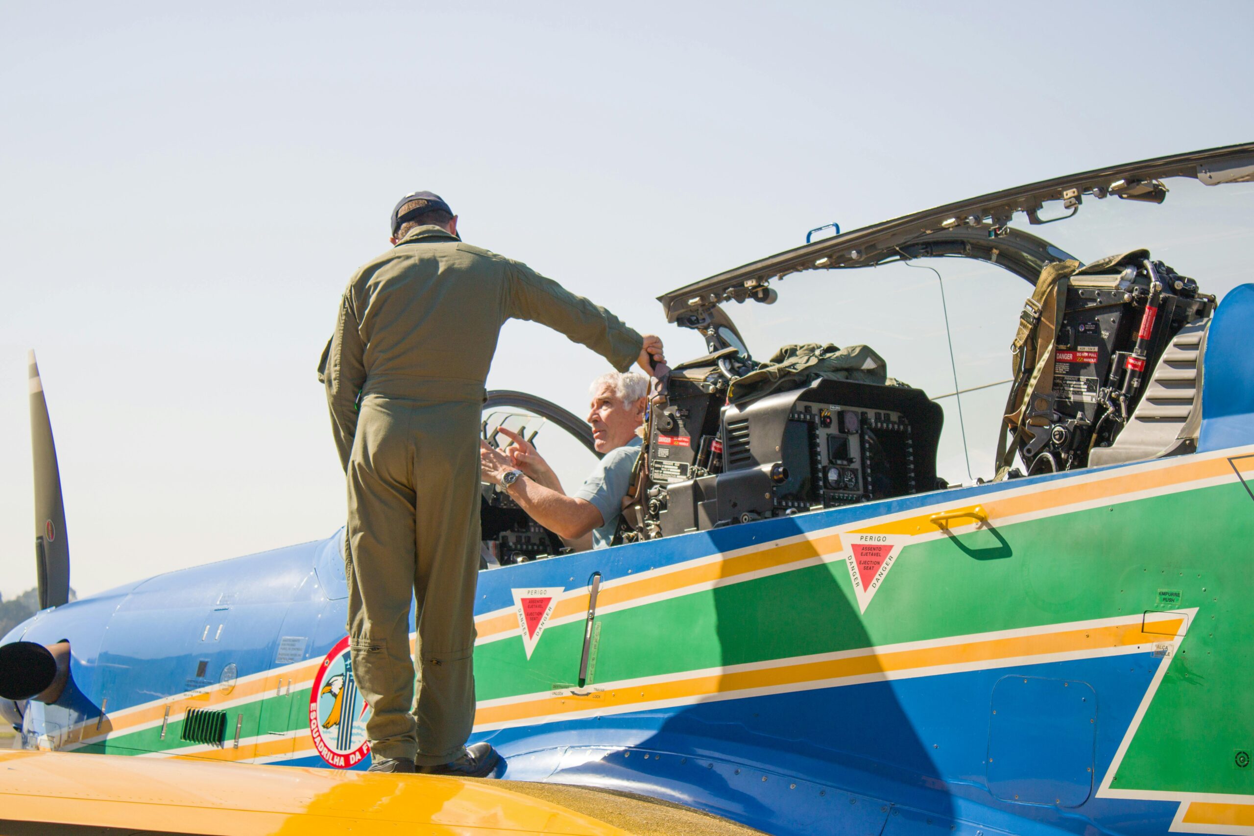 A military pilot standing by a vibrant aircraft, preparing for a mission under clear skies.